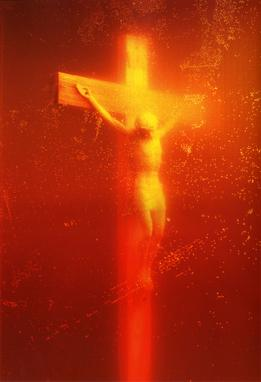 Piss Christ d'Andres Serrano : photographie d'un petit crucifix plongé dans un liquide, baigné d'une lumière rouge orangée parsemée de bulles.