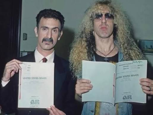 Frank Zappa, en costume, et Dee Snider, cheveux longs bouclés et lunettes noires, brandissent chacun un document de l'audition du Sénat des États-Unis.